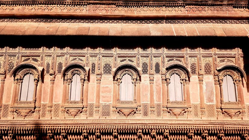 The facade of a historic building featuring a row of arches framed by detailed carvings, exemplifying classical architecture.