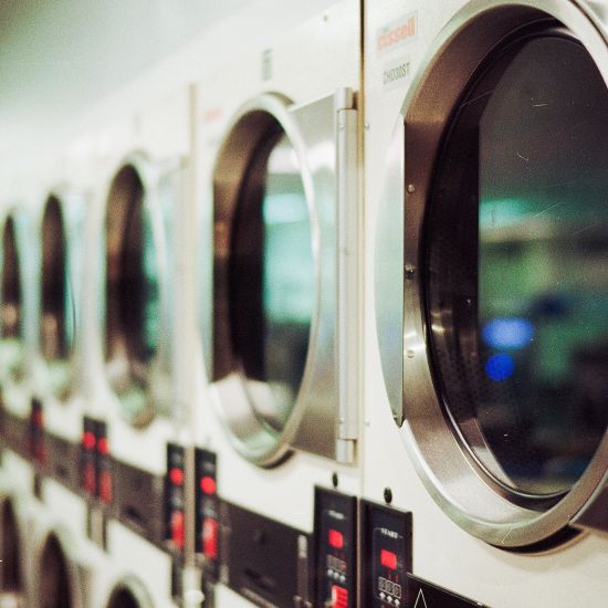 Many washing machines stacked next to each other inside a room