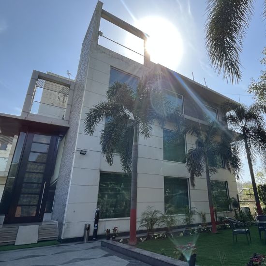 facade view of Yuhi Mansions surrouded by green coconut trees and a beautiful lawn outside the building that showcases tea-table and chairs for enjoying the view1