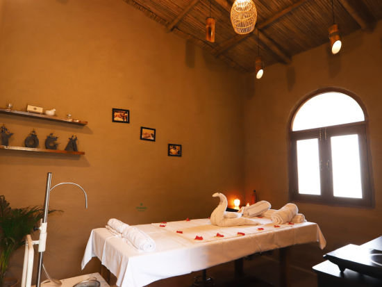 Themis Medival Wellness Centre displaying a massage table and rustic interior at Themis Mudhouse - A Nature's Retreat Resort & Wellness, oen of the best ayurvedic spa resorts near delhi