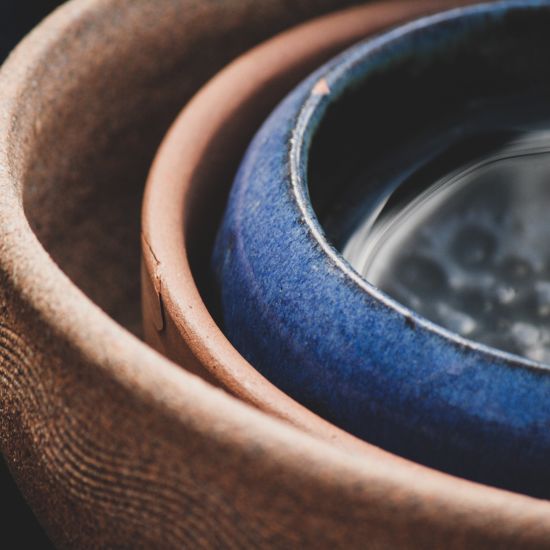 three Pots kept inside each other with two pots being brown and the last one being blue