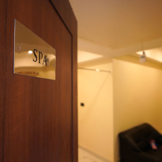 A wooden door with the golden name plate with spa written on it and a sofa on the corner