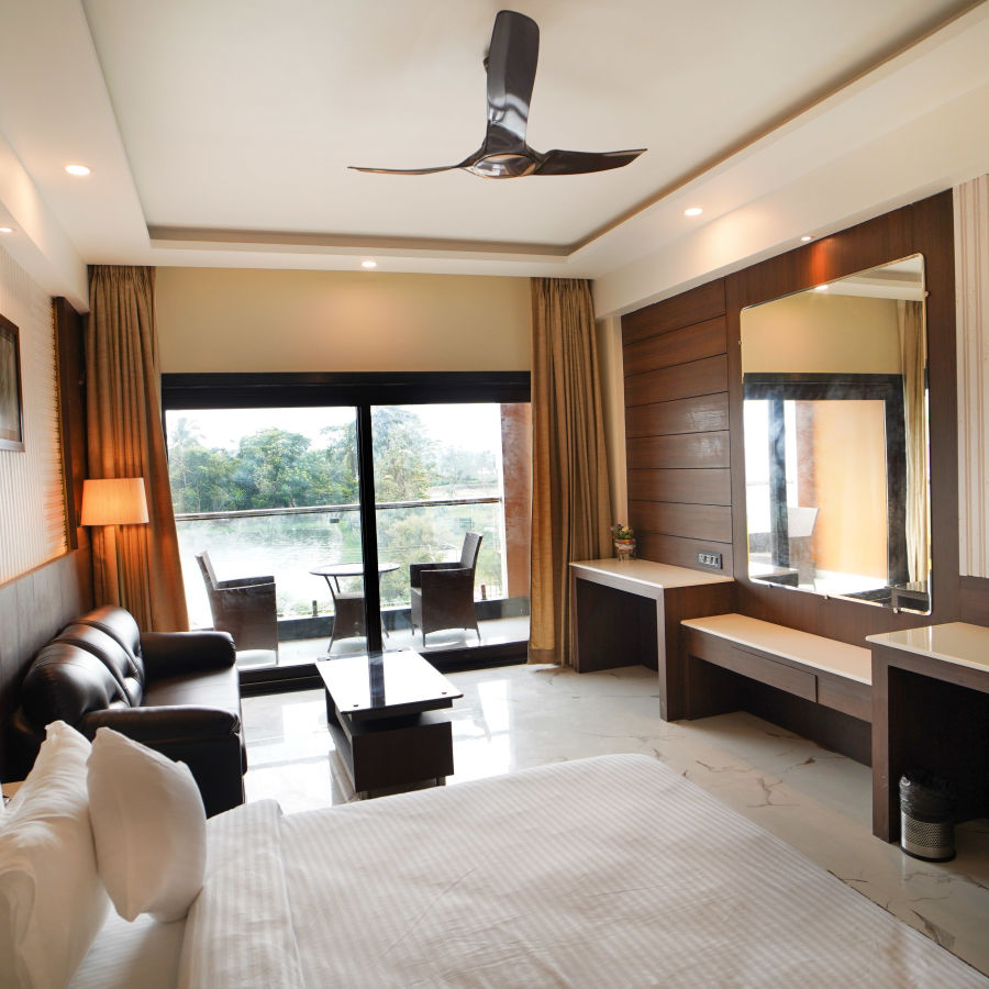 overview of a room with a double bed, sofa, coffee table, wardrobe and a wall mounted tv inside one of the rooms - Shanti Seaview Resort & Spa