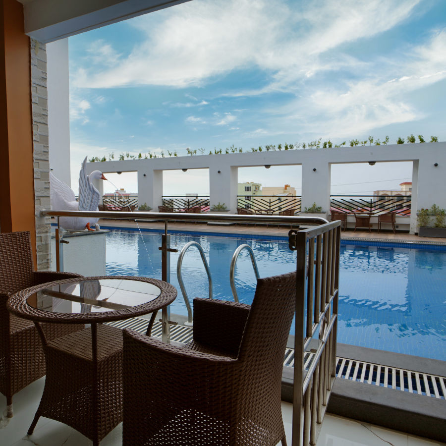 Seats in a balcony with a small table with views of the swimming pool inside one of the rooms - Shanti Seaview Resort & Spa