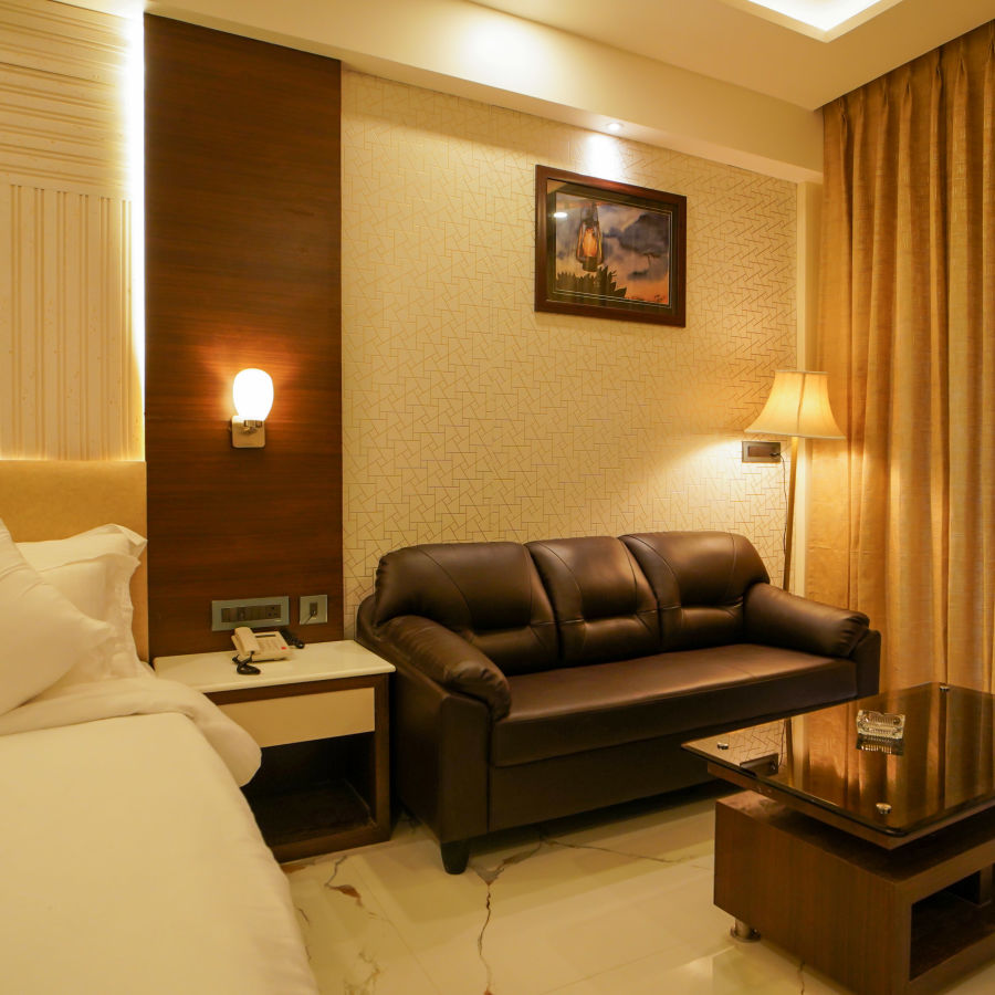 a leather sofa with a coffee table and a painting hung above the sofa inside one of the rooms - Shanti Seaview Resort & Spa