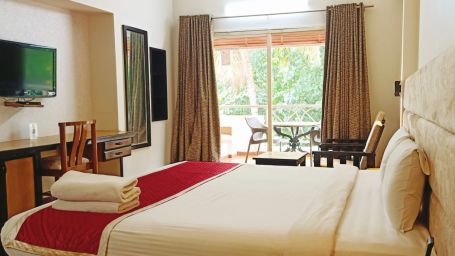 Damanganga Valley Resorts Pvt Ltd - the side view of the king size bed in the bedroom attached to a balcony of the Executive Room in Daman