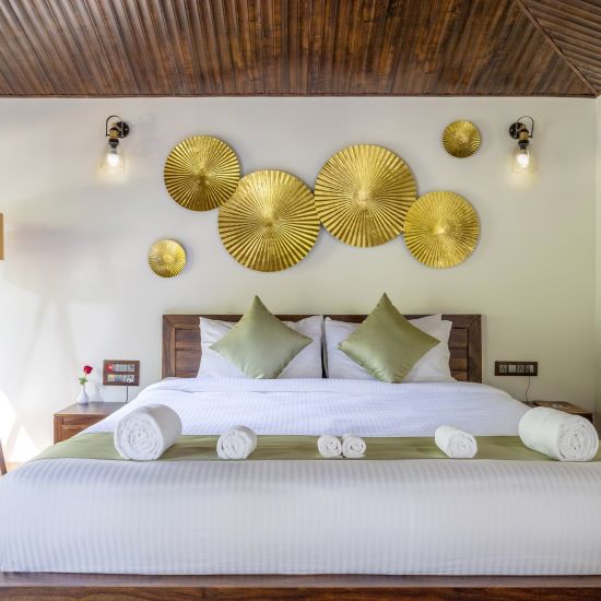 alt-text A view of a large bed in our suite with a night lamp by the side - Stone Wood Nature Resort, Gokarna