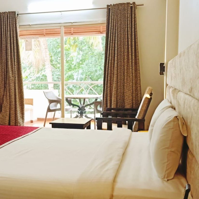 Damanganga Valley Resorts Pvt Ltd - the side view of the king size bed in the bedroom attached to a balcony of the Executive Room in Daman