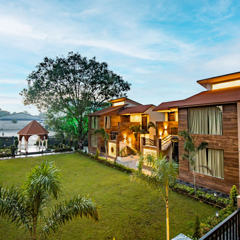 A scenic view of our hotel nestled near the lush lawn beneath the expansive open sky - Wedlock Greens Hotel & Resorts