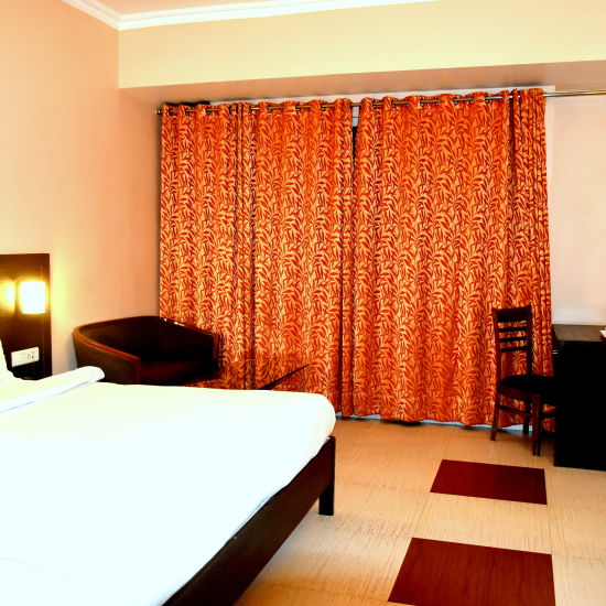 A sideview of Executive Room with bed, TV and a desk | Hotel City Inn, Varanasi