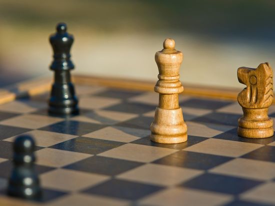  An image featuring a chessboard with chess pieces on top