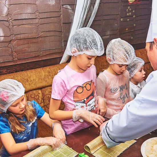 a chef teaching a group of children how to prepare food in a kitchen