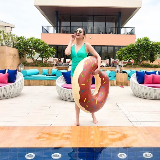 Woman in a neon green bathing suit holding a donut shaped swimming ring