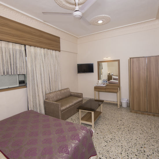 alt-text room with king size bed and sofa in dadar at hotel bawa regency