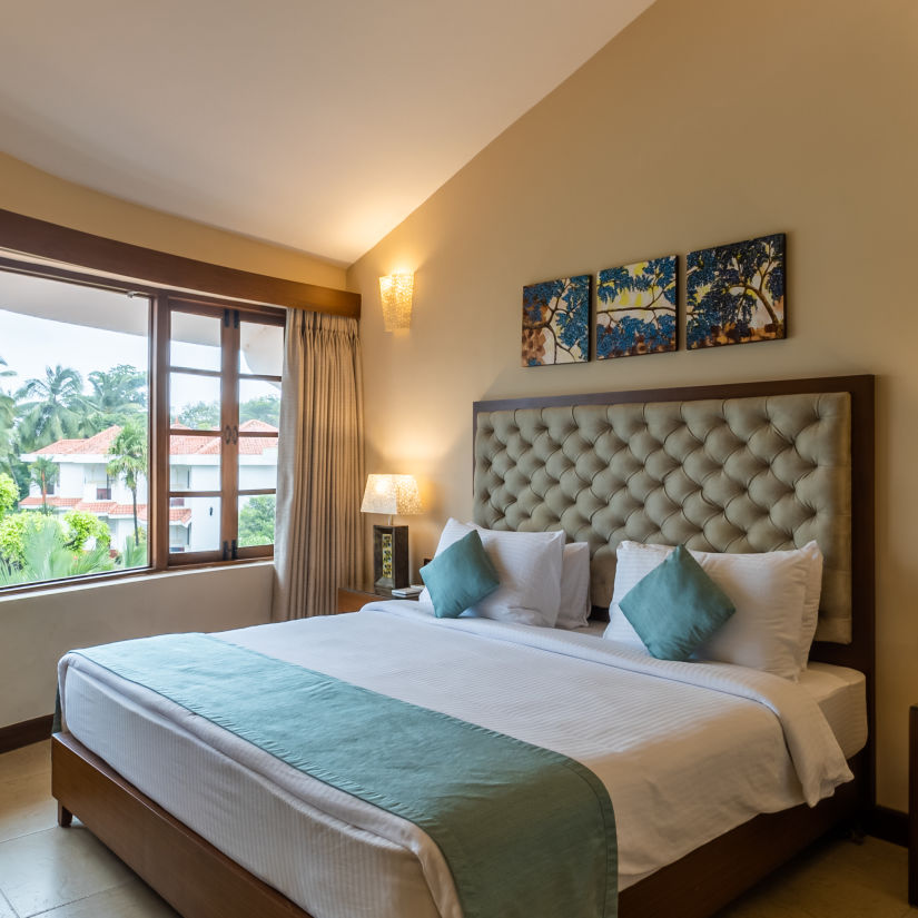 suite with a cosy king size bed and mellow lighting at heritage village resort and spa goa