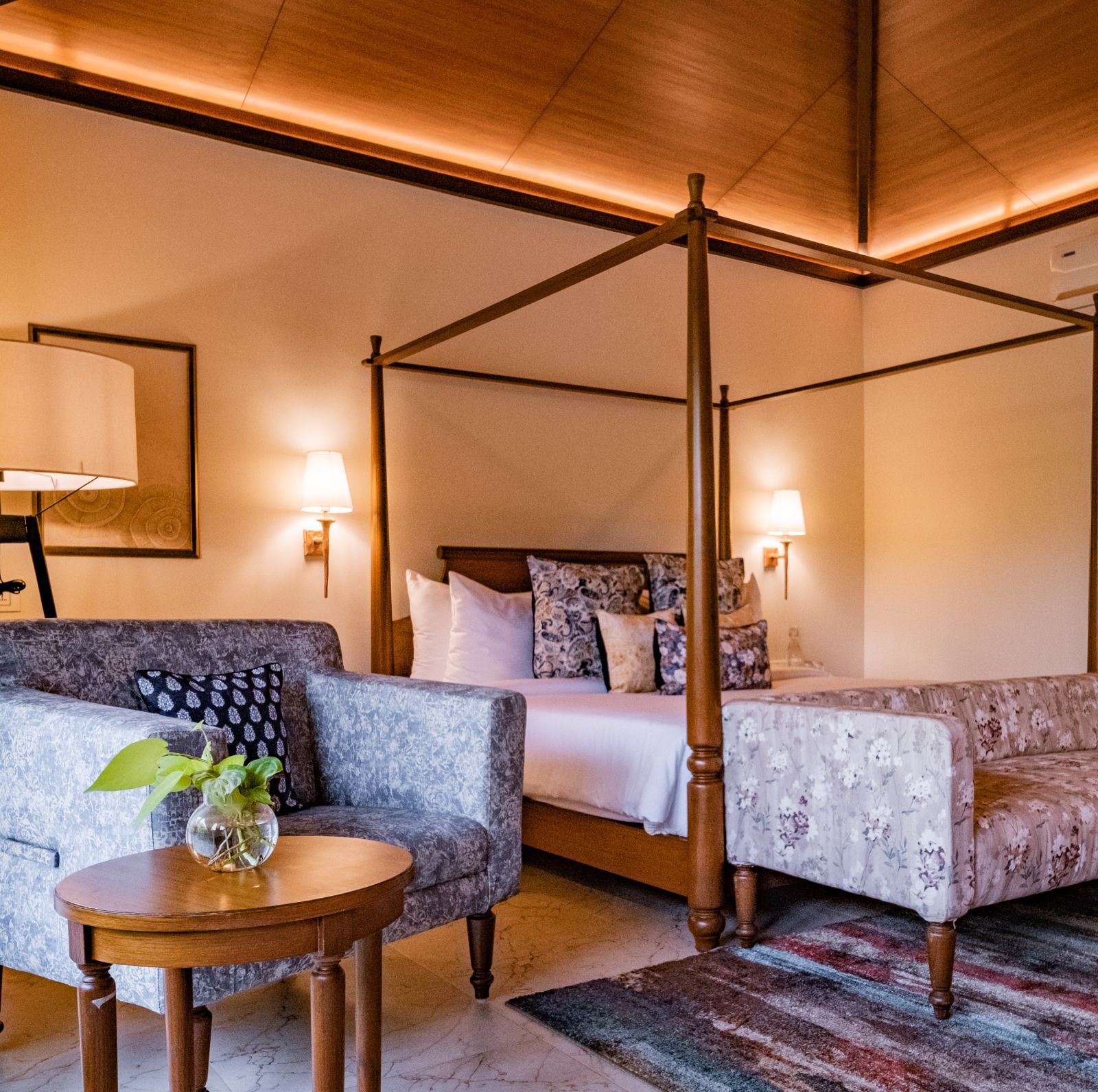 a four poster bed and an armchair in one of the rooms at our wellness retreat in karnataka