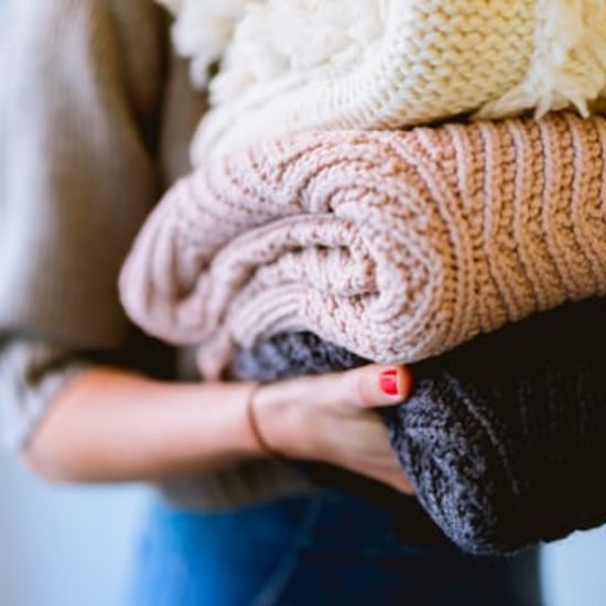 a woman holding folded woollen clothes