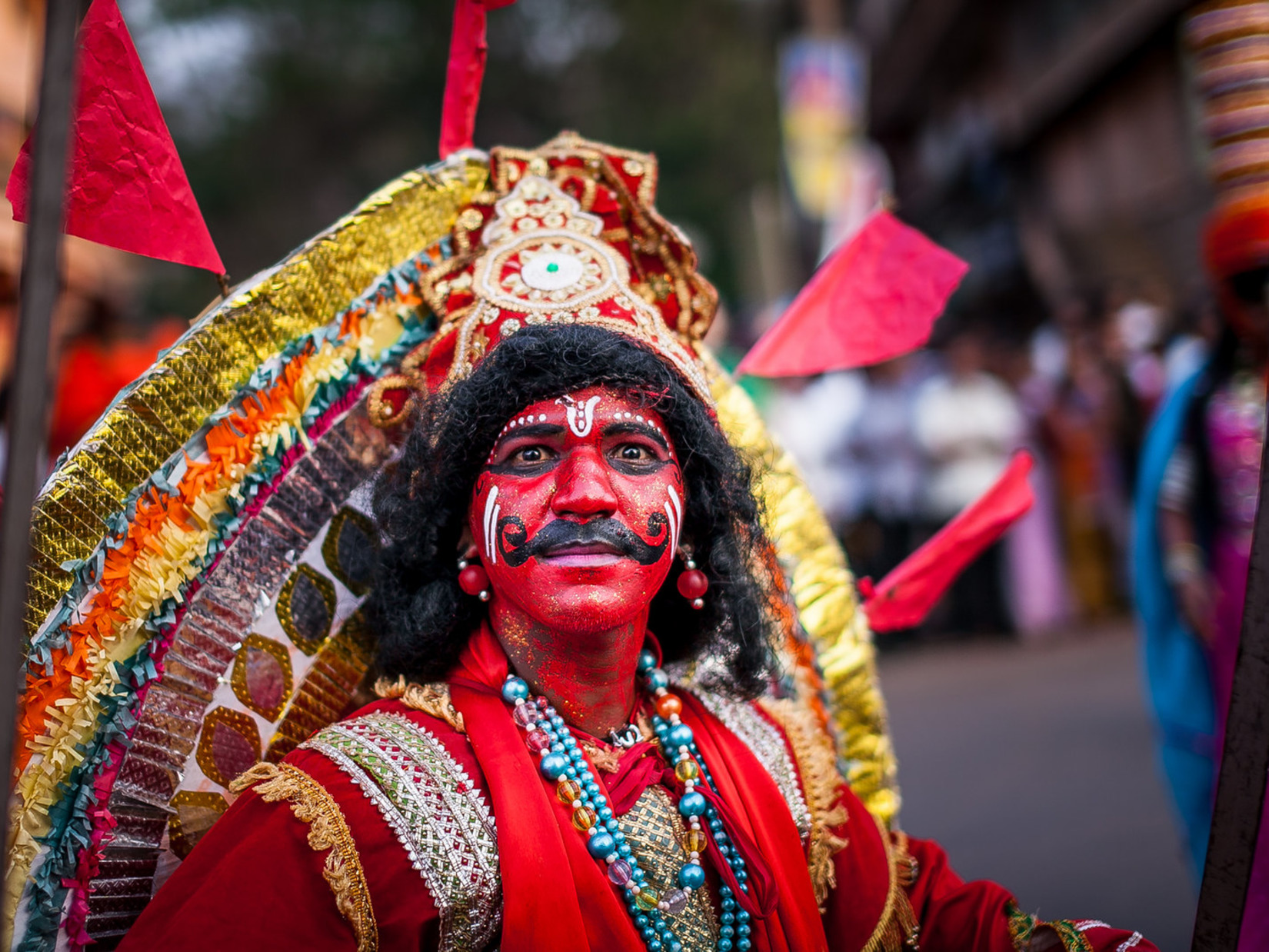 Person with a painted red face and moustache plays a character