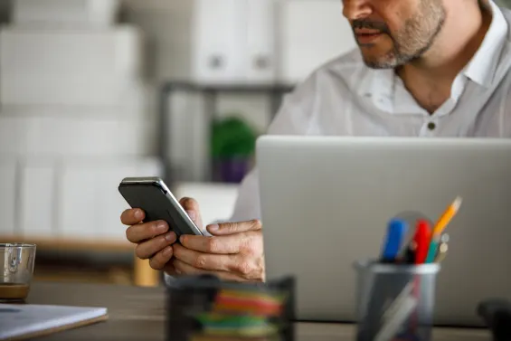 man texting and working on his laptop