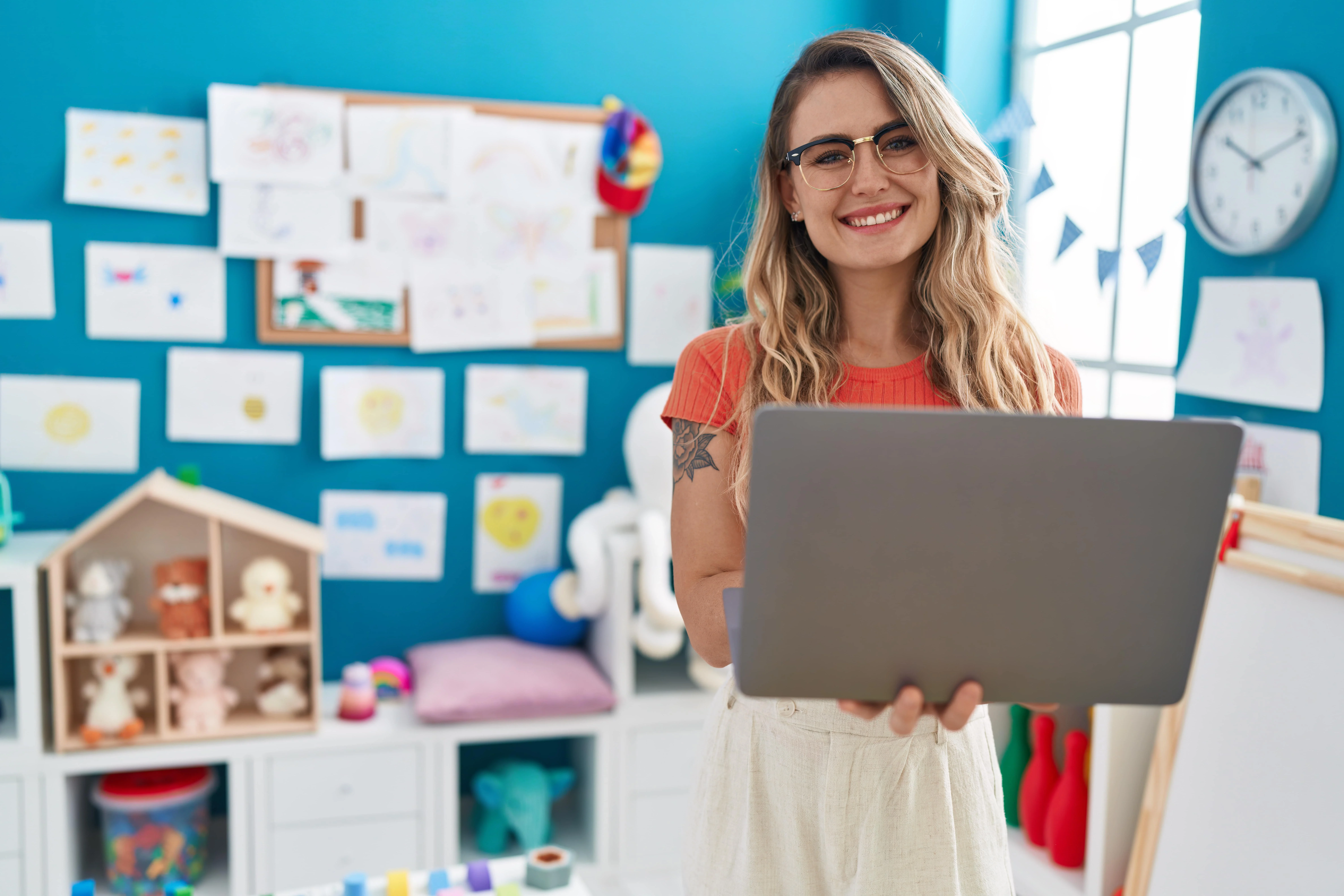 young teacher with laptop standing in classroom