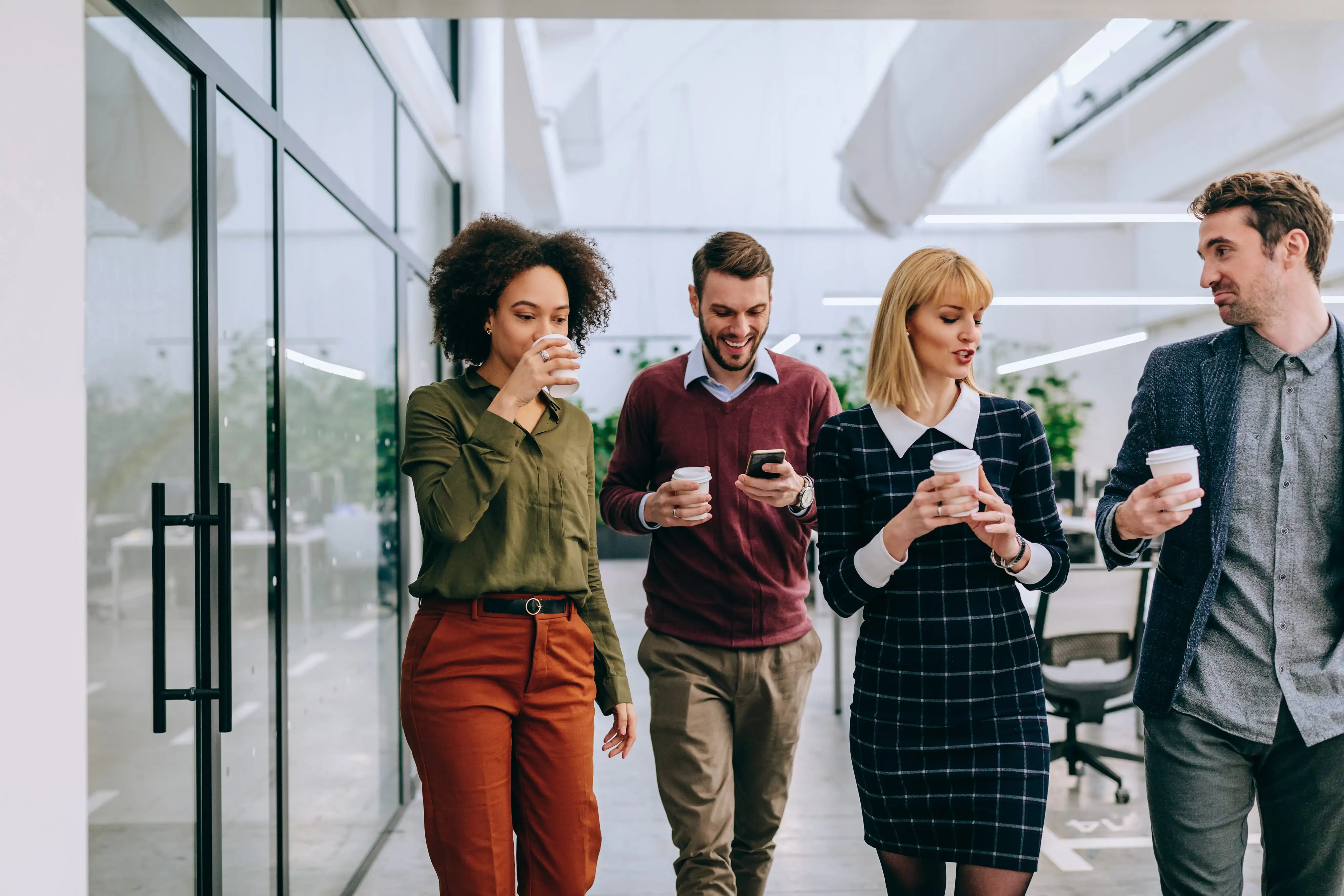 colleagues in office building walking together with cups in hands