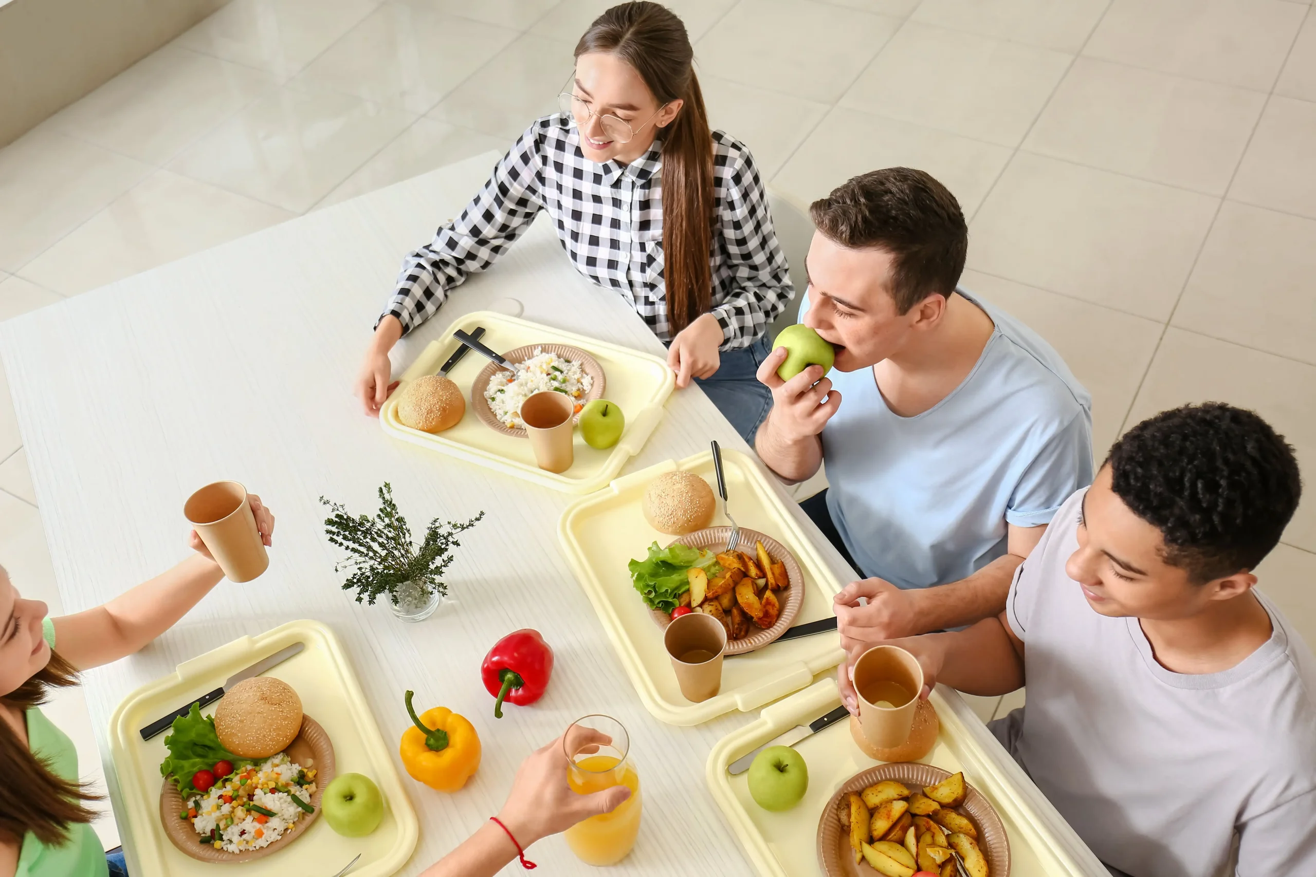 people at table in cafeteria with food trays for lunch