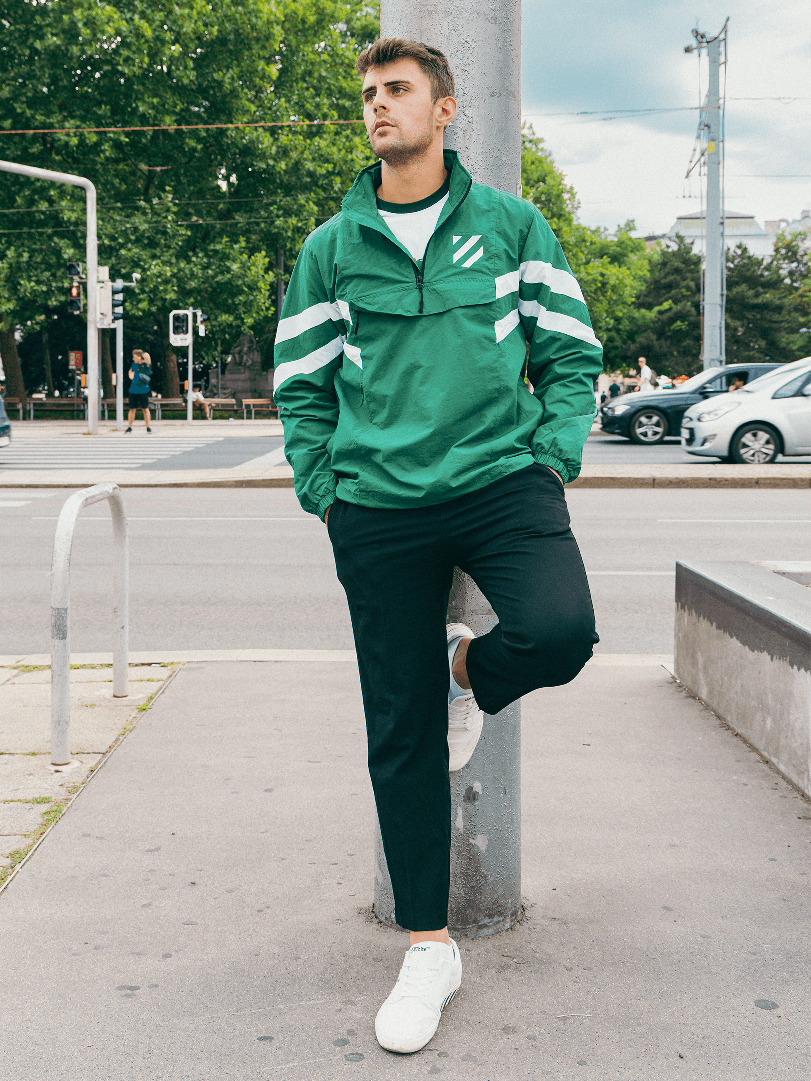Grüner SK Rapid Windbreaker Wappenschild mit Half-Zip und weißen Streifen in urbaner Umgebung.