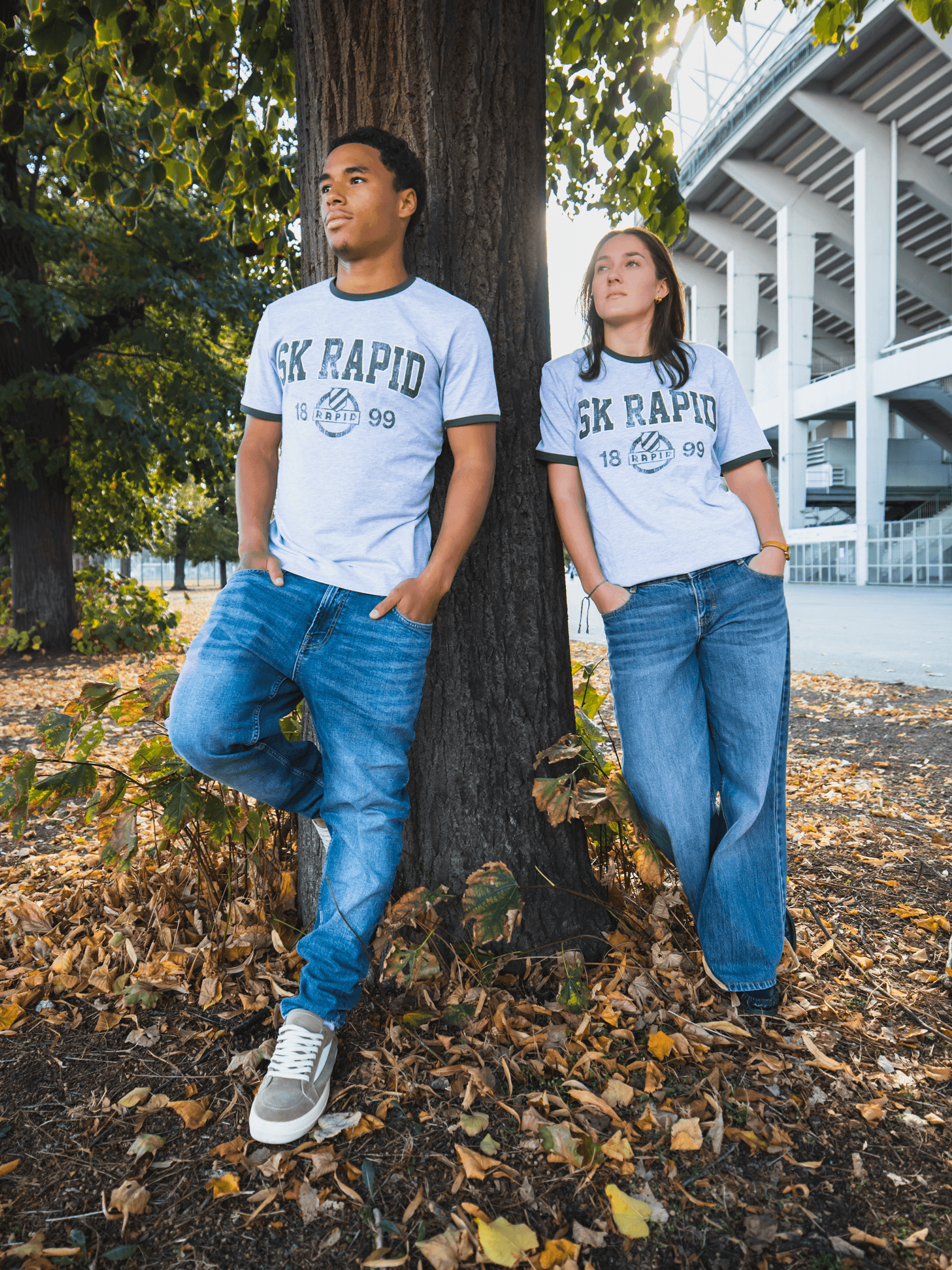 SK Rapid Vintage T-Shirt in Grau mit Retro-Motiv, getragen von zwei Fans beim Stadion.