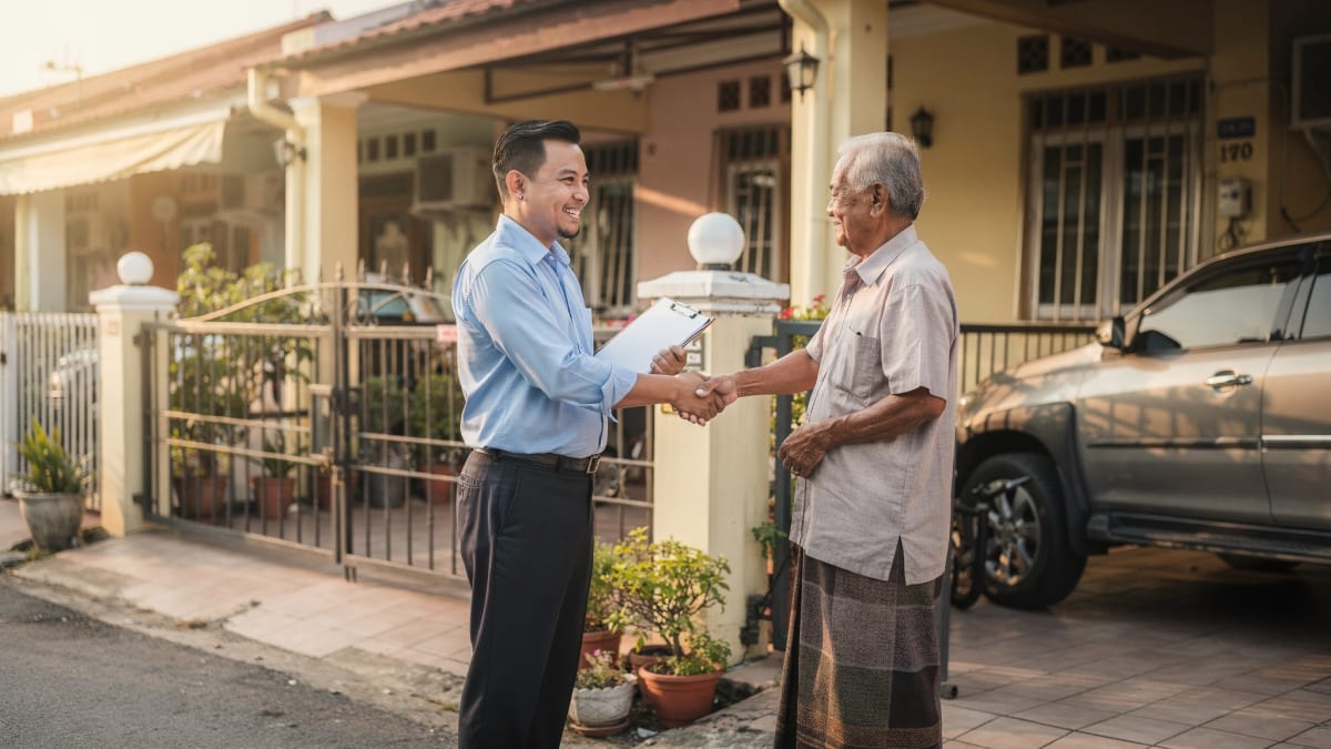 Perunding hartanah berjabat tangan dengan pemilik rumah di pintu pagar