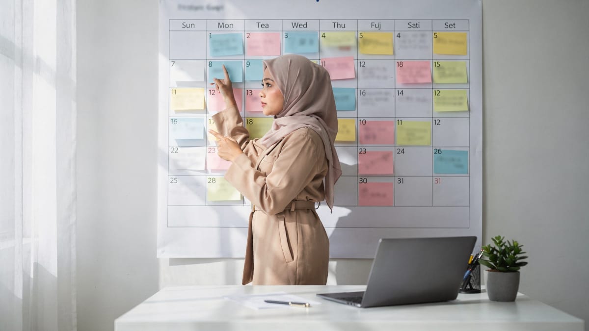 Perunding hartanah merancang pelan 90 hari di kalendar dinding dengan nota pelekat