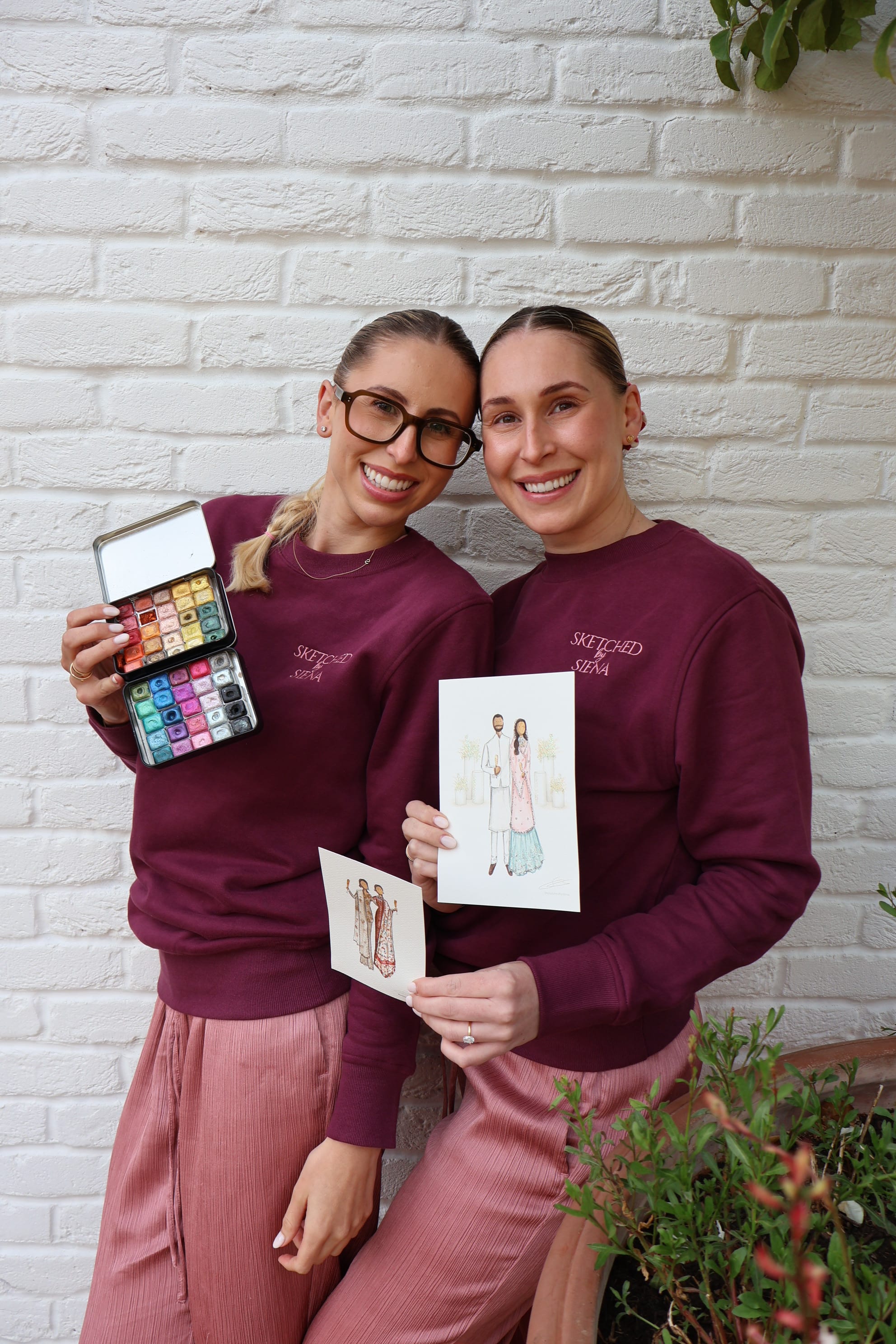Siena and Ellie holding up paintings