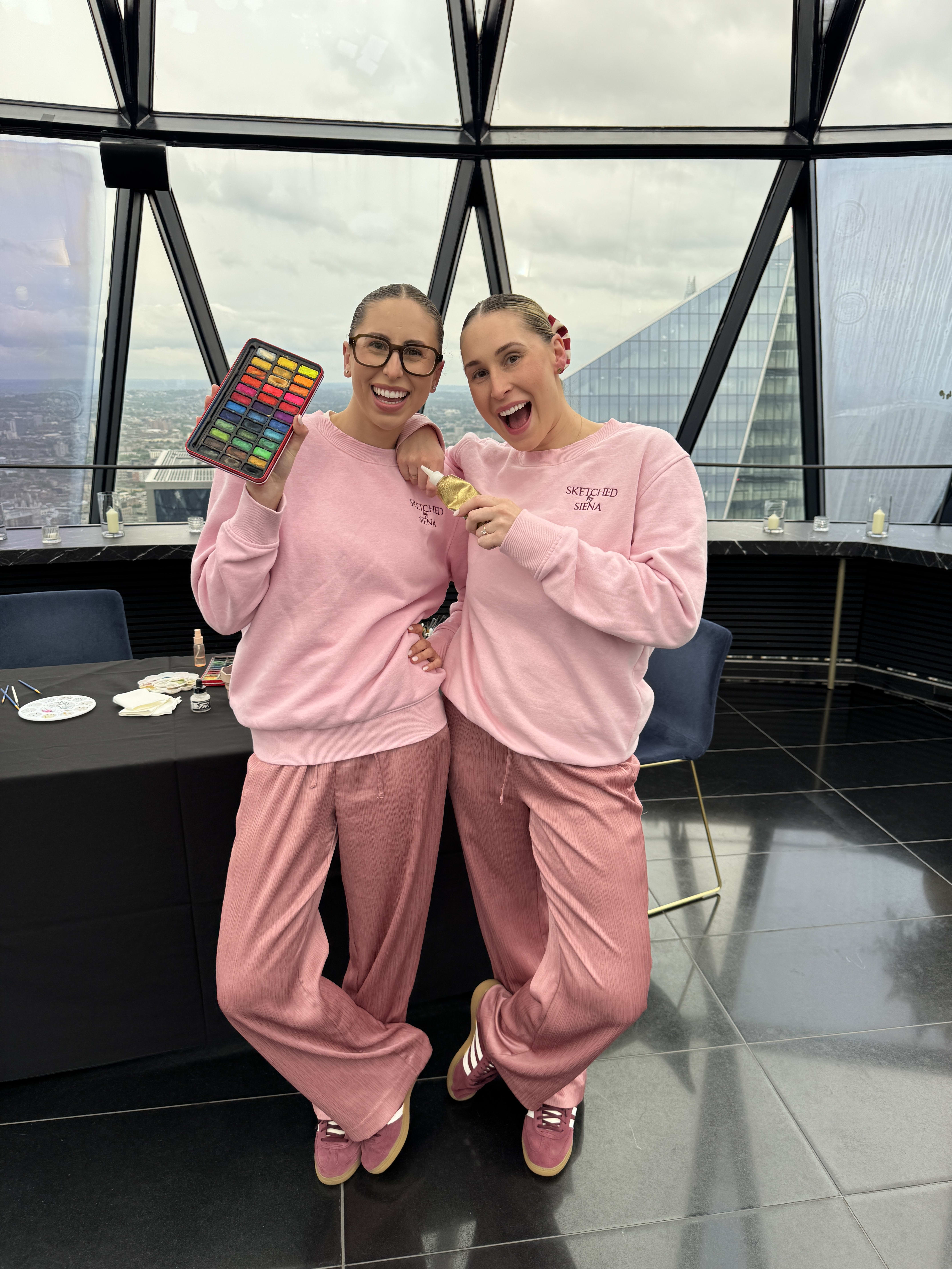 Siena and Ellie in a high rise building at a live sketching event
