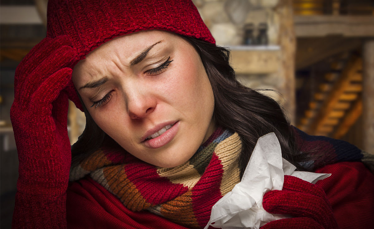 Woman with a cold wearing hat and mitts with red nose