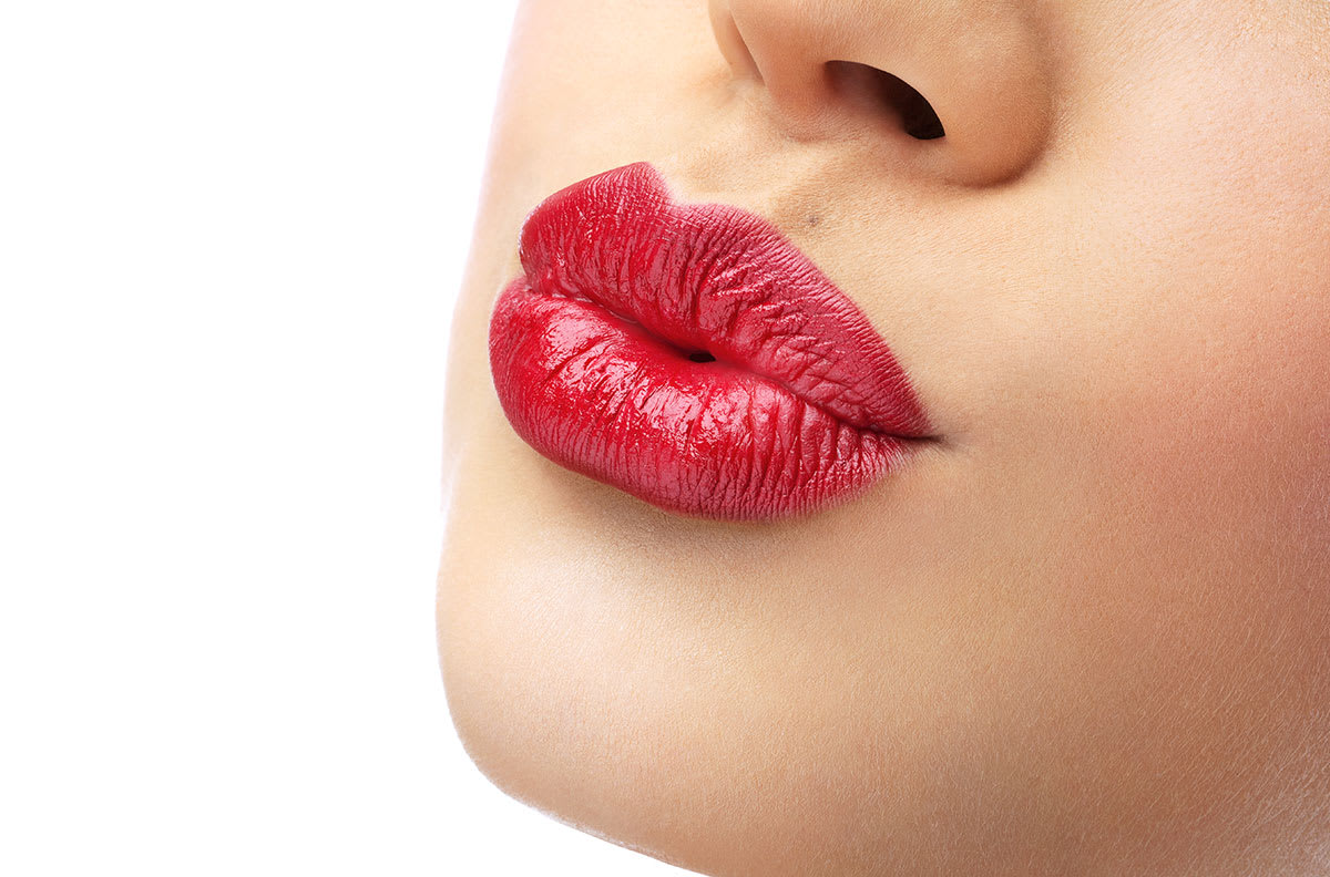 Woman's red lips pursed in a kiss.