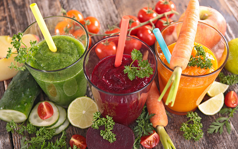 Cups filled with freshly pressed vegetable juices for healthy skin.