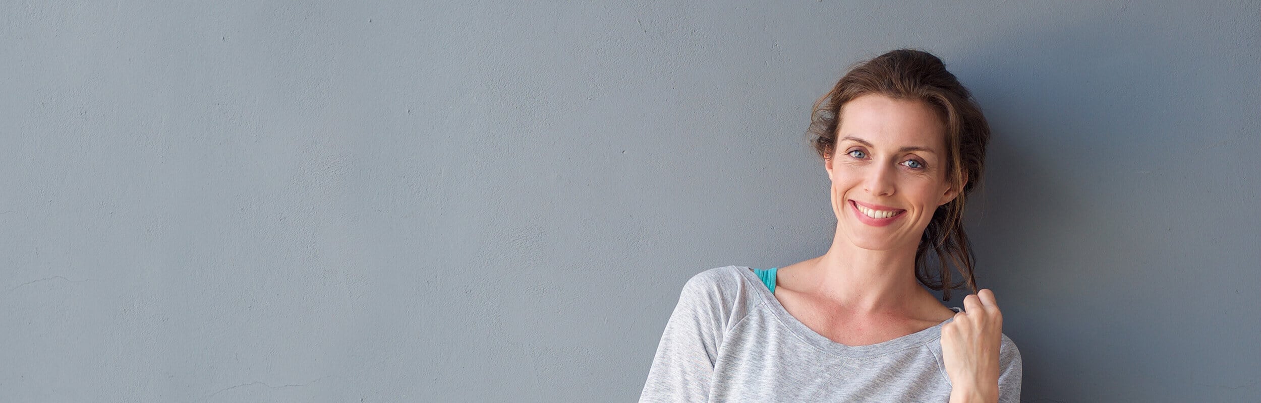 older woman smiling on grey wall
