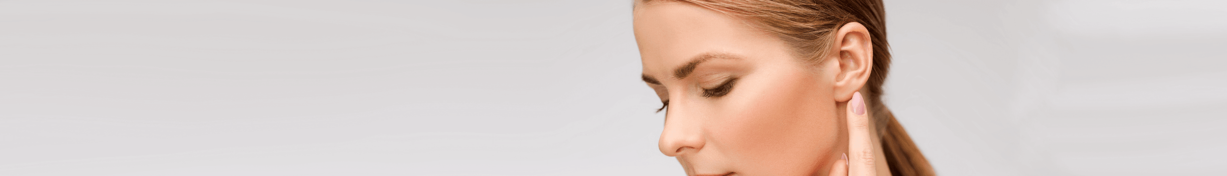 woman pointing to earlobe to show balanced ear proportion after ear surgery