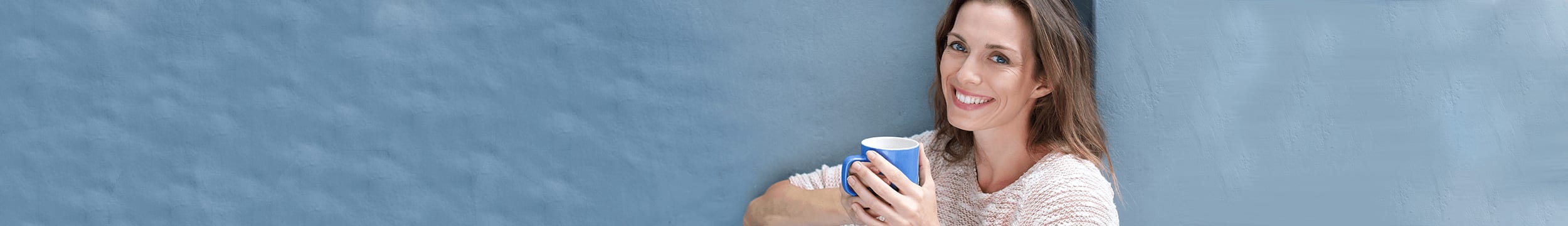 Older woman with brown hair after facelift smiling and drinking coffee