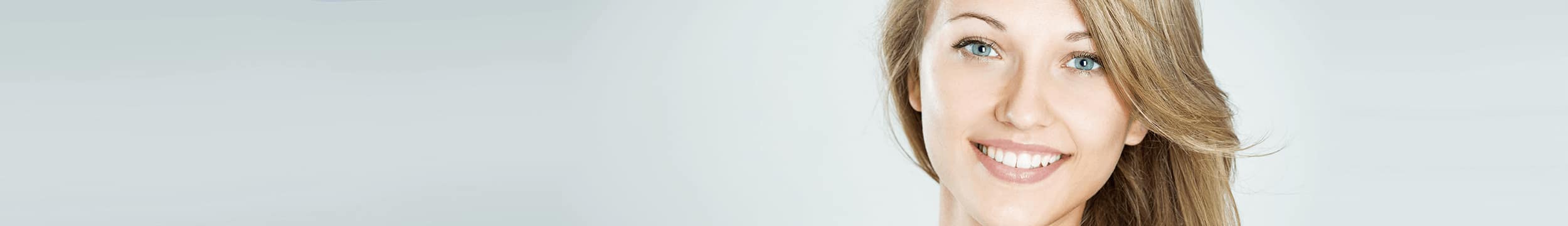 young woman with blonde hair and blue eyes smiling, showing clear complexion