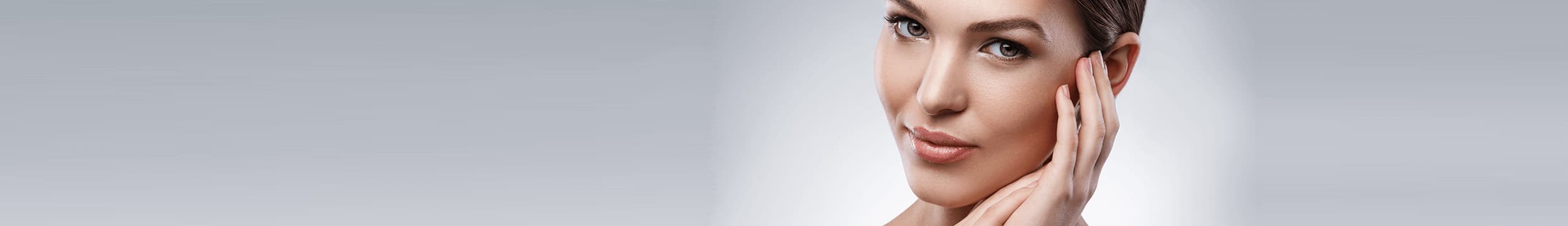 brunette woman tilting head to side and smiling on white background