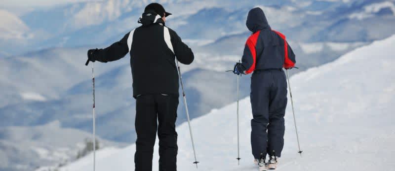 two people with skis looking over a mountain