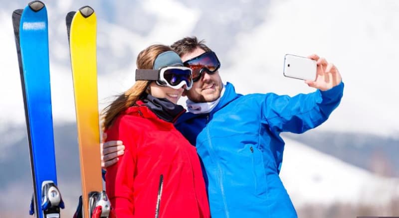 young couple skiing with their cell phone