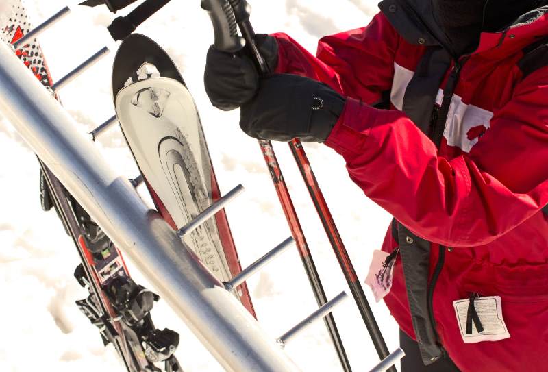 person holding ski boots and poles person holding ski boots and poles