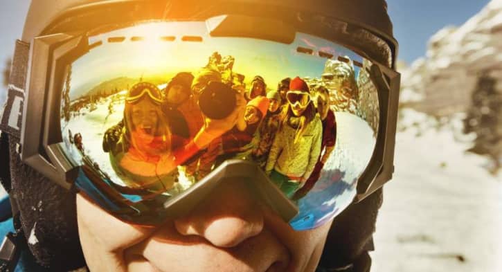 Woman skiing with glasses on wearing ski goggles otg