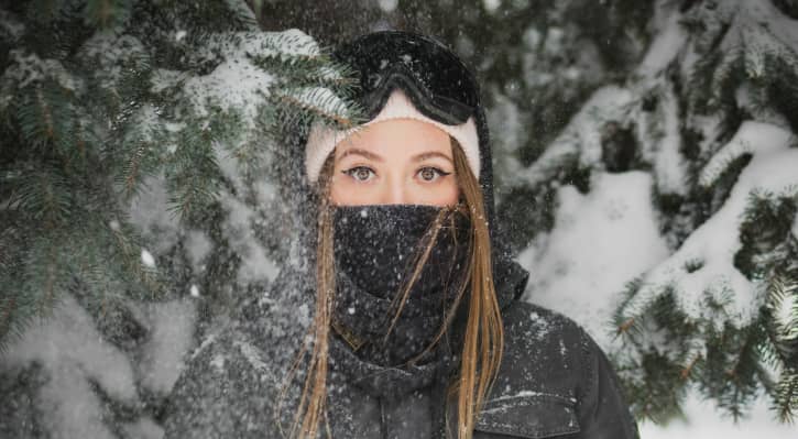 Lady keeping neck and face warm with a neck gaiter in cold weather outdoors