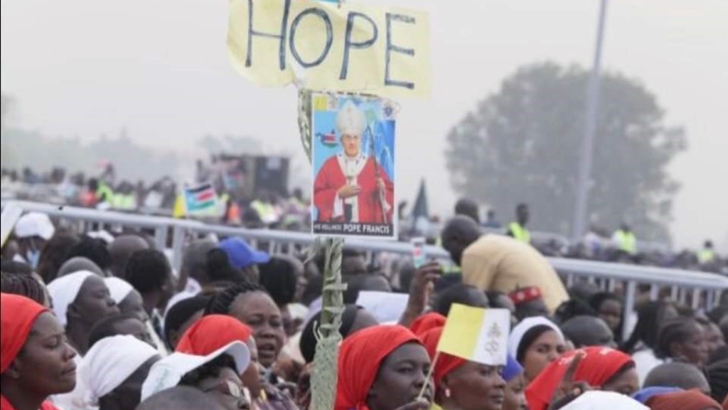 Bilde er fra Pave Frans sitt besøk i Sør-Sudan. En stor folkemengde med en plakat av paven og over den står det håp.