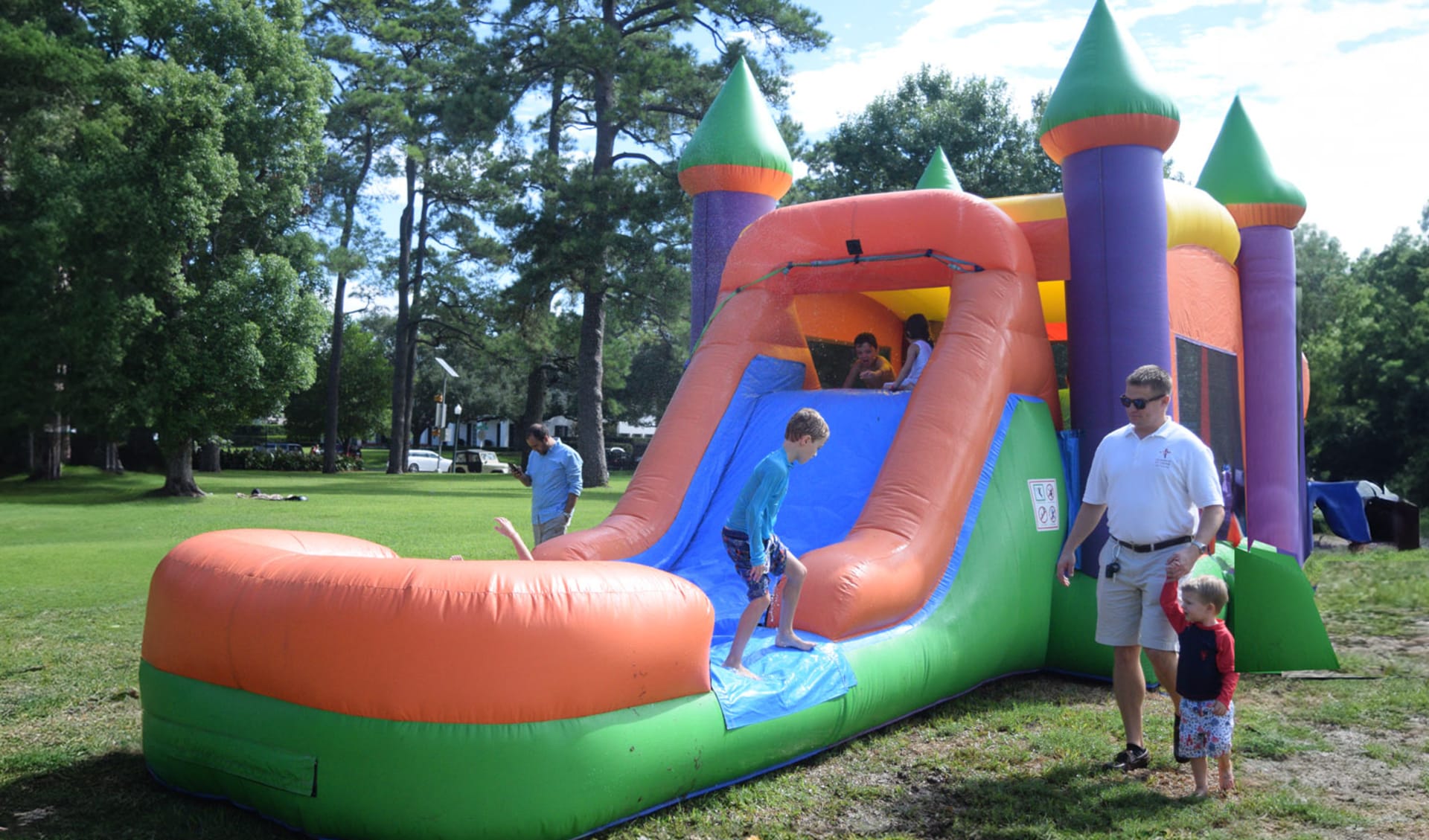Colorful 3-in-1 bounce house with orange slide rental in Houston, ideal for Kingwood backyard parties with wet or dry play