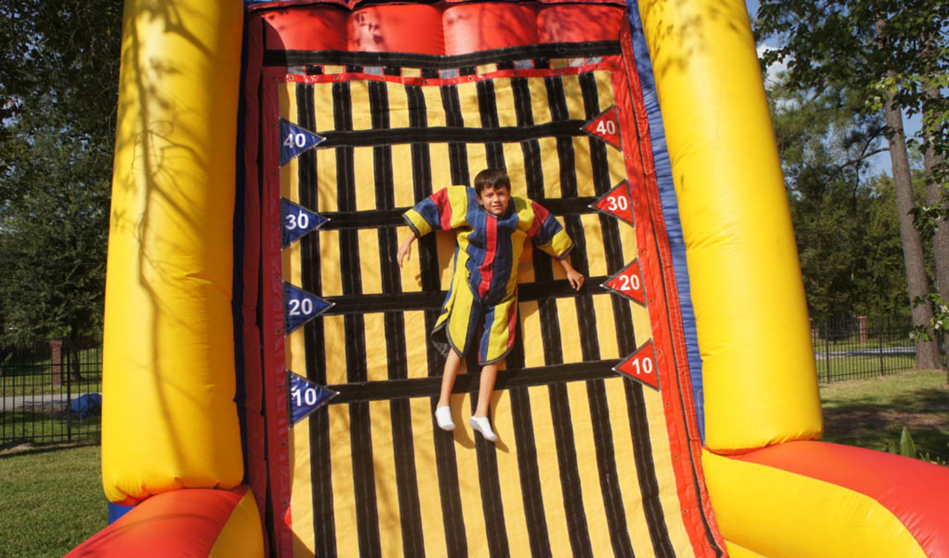 Velcro Wall renta en Dallas — niño escalando pared inflable amarilla y roja, ideal para eventos hasta 150 personas en Grand