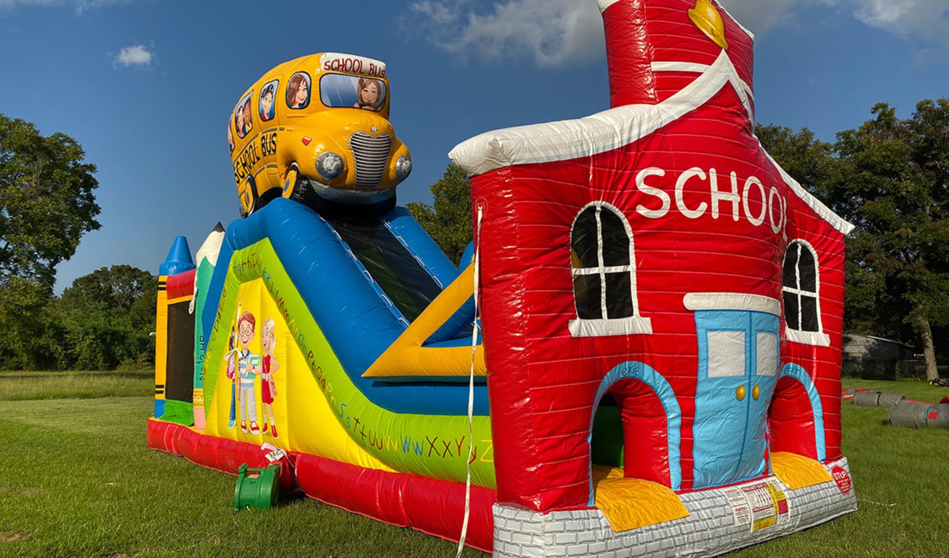 Renta de obstáculo School House & Bus con toboganes duales, disponible en Austin — perfecto para eventos en Pflugerville.