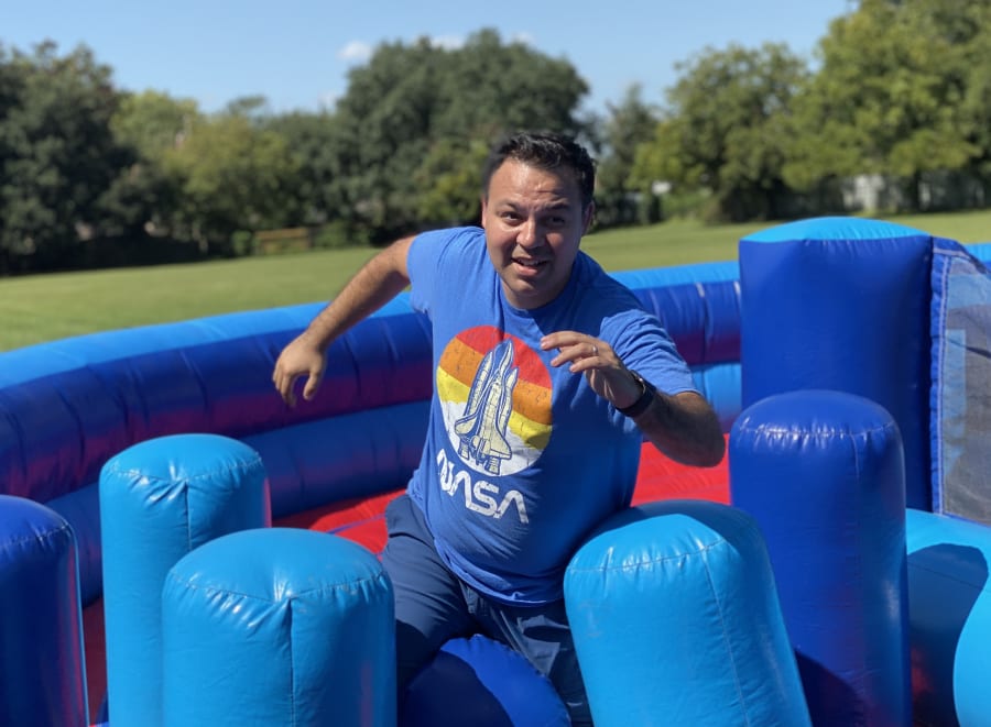 Robert De Los Santos running through an interactive inflatable in a NASA shirt